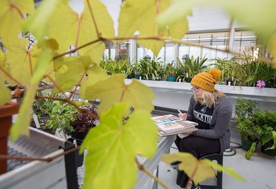 girl painting in greenhouse