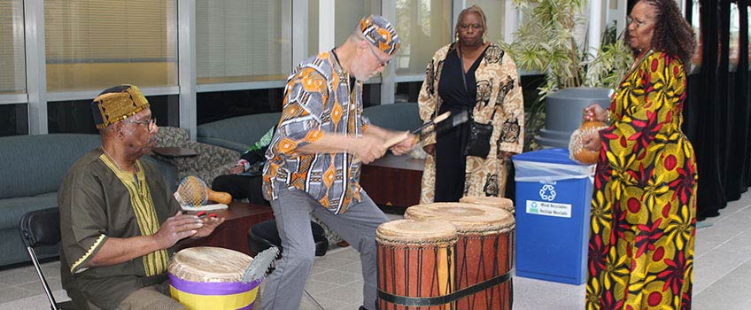 two women and two men dancing and playing drums 