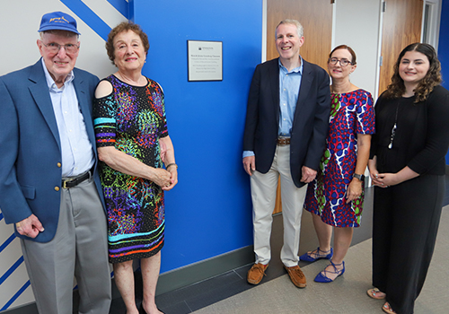 two men and three women standing by plaque