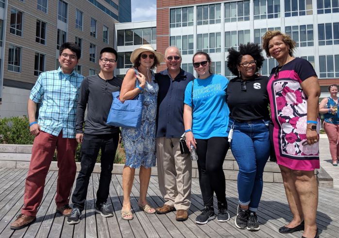 men and women standing on boardwalk 