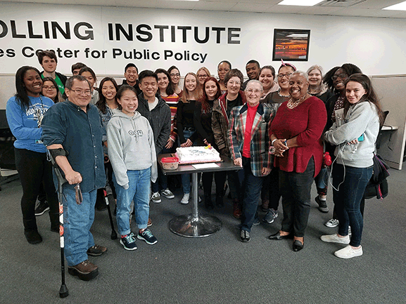 group of men and women gathered around cake