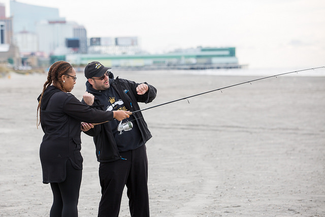man helping woman with fishing pole 