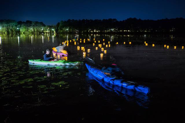 two kayakers on lake at night with lanterns on water