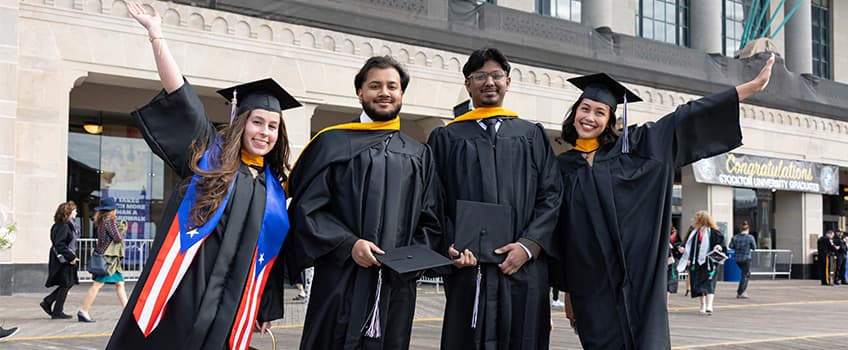Graduates posing on boardwalk outside 