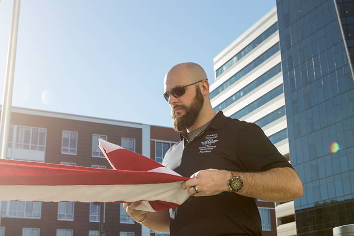 Ryan Luurtsema (pictured), Dylan Carr, and Kirsten Chervenak, representing the Stockton Student Veteran Organization (SVO), lead a flag raising ceremony at Stockton University Atlantic City.