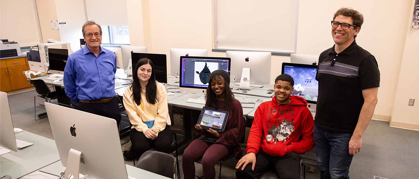 Two older adults and three college students pose in a computer lab