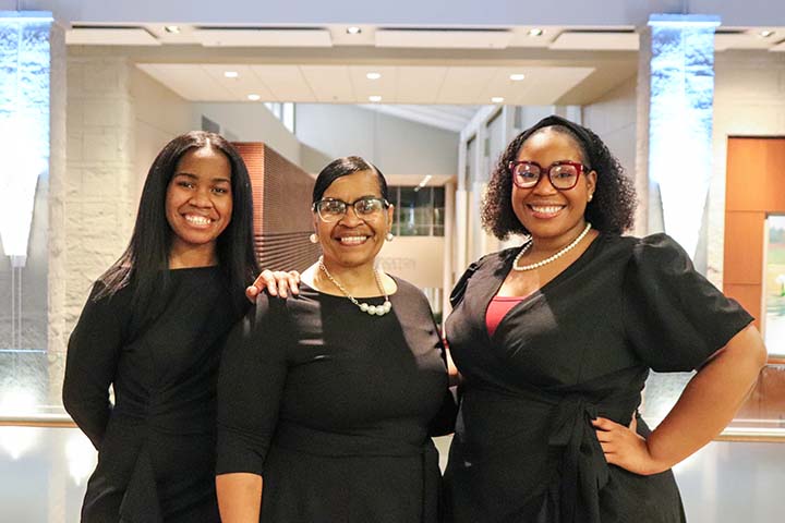 Alicia Jenkins, Beatrice Jenkins, and Alexis Jenkins wear matching black outfits while posing on the second floor of the Campus Center