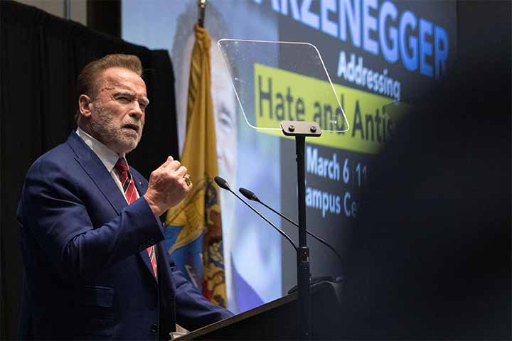 Arnold Schwarzenegger stands behind a podium to address a crowd 