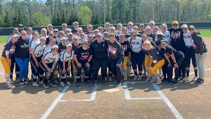 Softball players from Stockton and Rowan pose in front of the pitchers mound