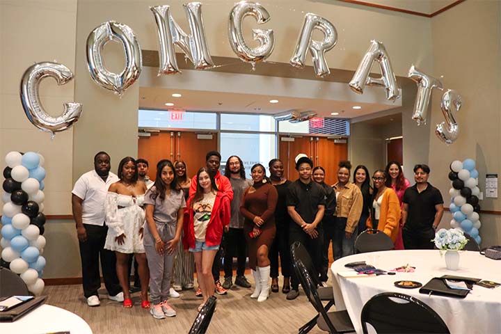 A group of students pose under letter balloons that spell out Congrats