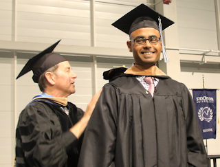 Amar Shah is congratulated on earning his MBA by Business Studies Professor Michael Busler at the Master’s and Doctoral Commencement held May 10.