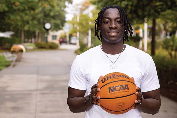 DJ Cambpell wears a plain white t shirt and holds a Wilson basketball