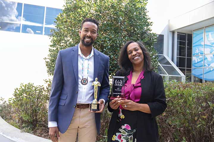 Aaron Moss and Donni Allison each hold an award