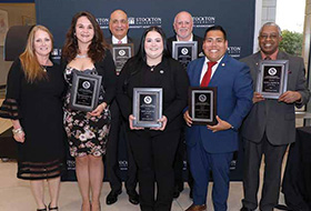 A group of alumni honorees holding their plaques