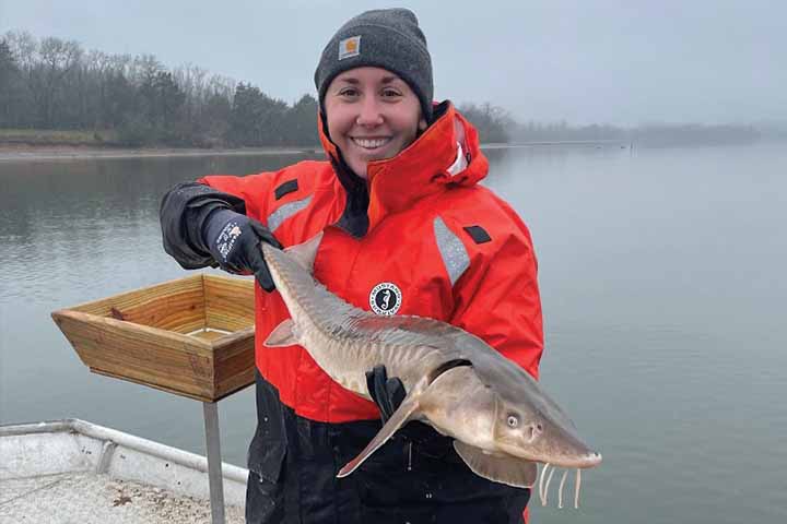 Jessica Radich in red coat holding a large fish