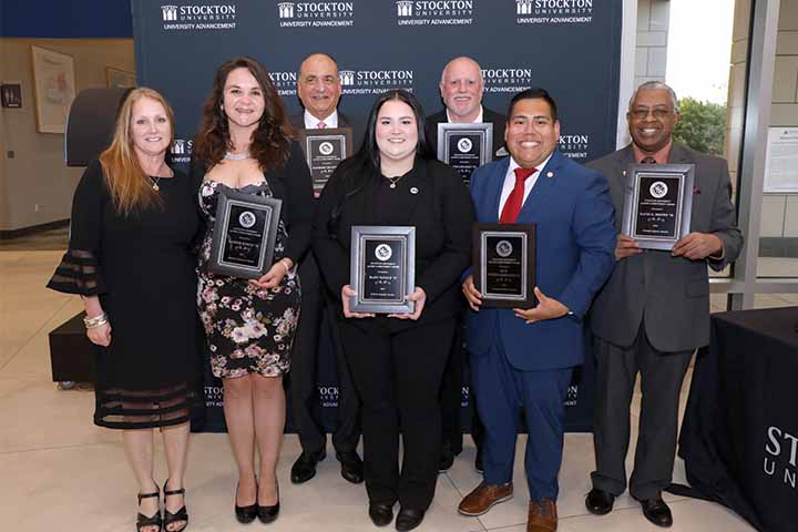 The Six alumni honorees pose with their plaques and Sara Faurot