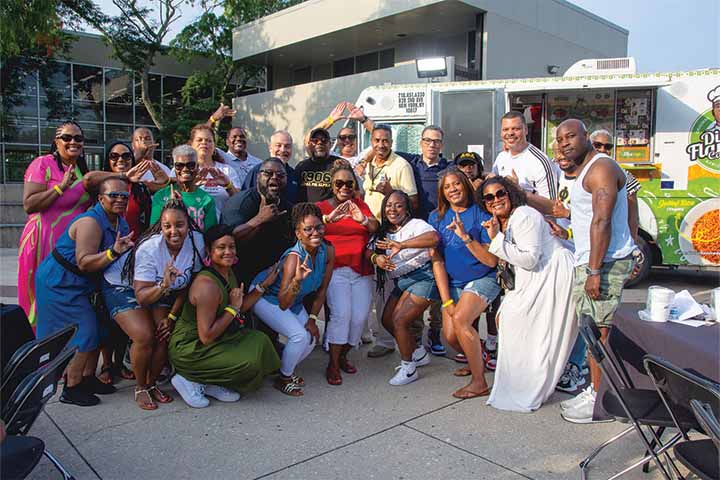 A group of black alumni pose in front of a food truck on Stockton's main campus