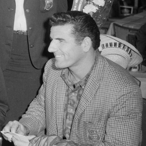 Black and white photo of Don Bragg wearing an olympic jacket at a ceremony