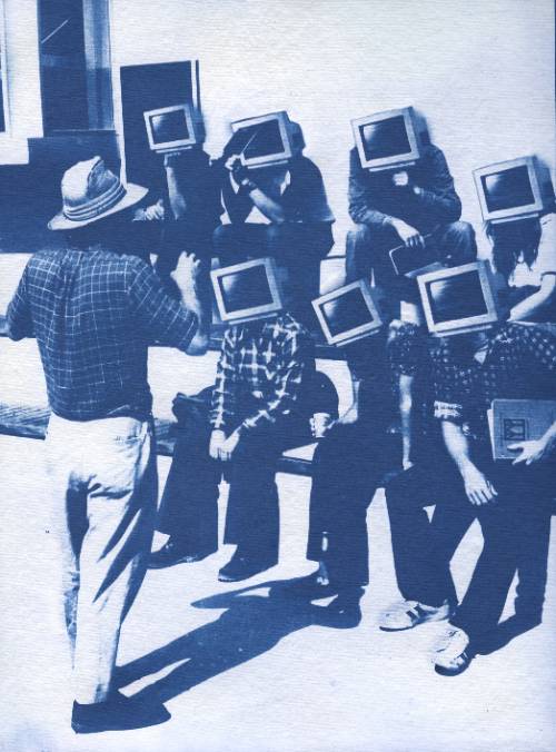 Students listening to a lecture outside on stone bleachers with computer monitors for heads