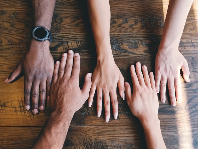 image of five hands flat on a desk