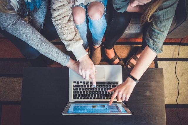 three people pointing to a laptop screen