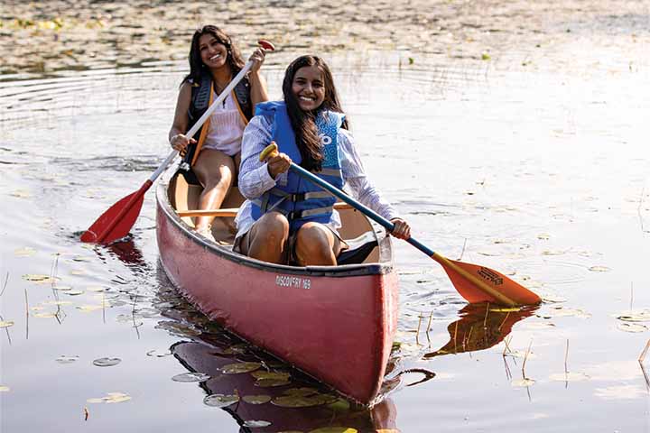 Two students smile while canoeing on Lake Fred
