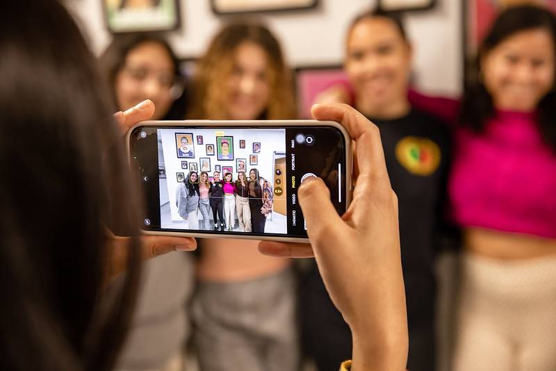 Selfie time! Girls taking a selfie in front of pictures of women at WGSC